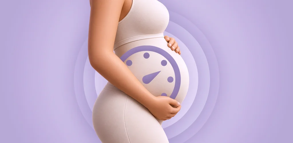 A pregnant woman in a soft beige top holding her bump